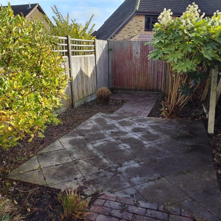 A person using a pressure washer to clean a patio surface.