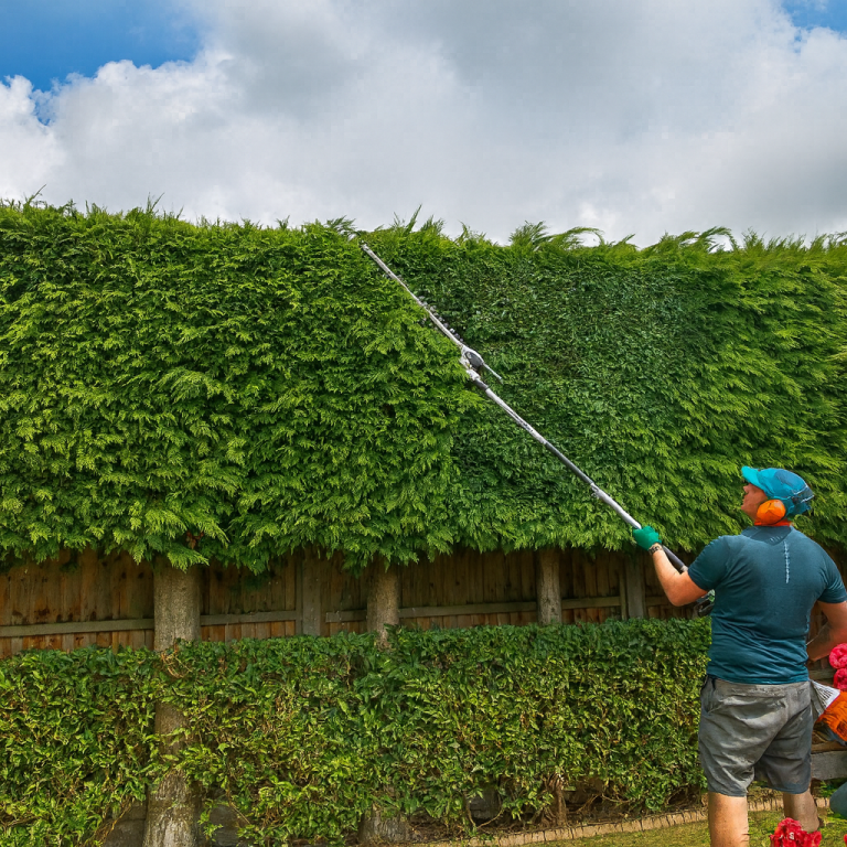 A man using a pole to clean a window from outside a two-storey house.