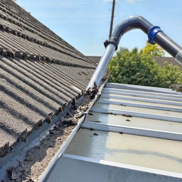 A person using a pressure washer to clean a patio surface.