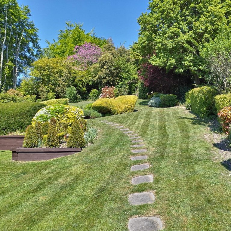 A man using a pole to clean a window from outside a two-storey house.