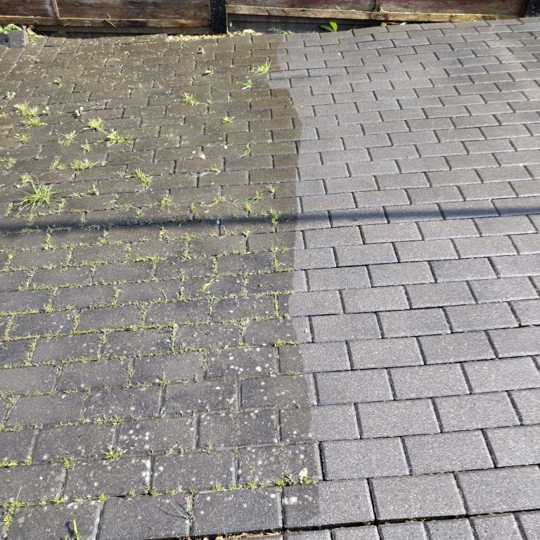 A man using a pole to clean a window from outside a two-storey house.