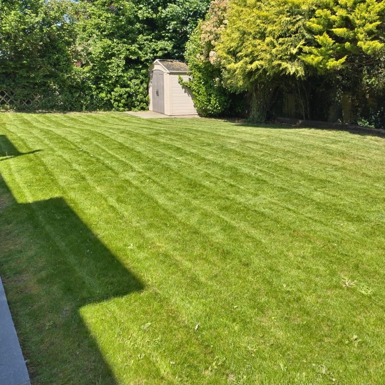 A man using a pole to clean a window from outside a two-storey house.