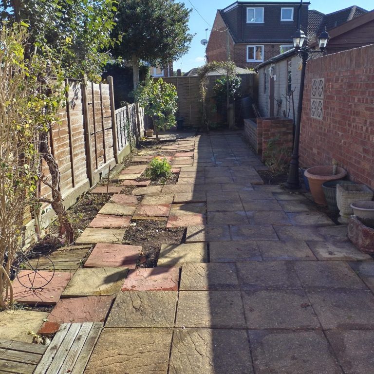 Front garden of a house with a patchy lawn and stone pathway.
