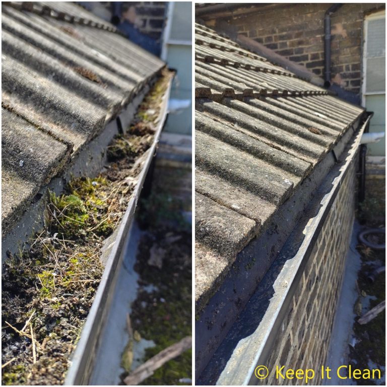 A man using a pole to clean a window from outside a two-storey house.