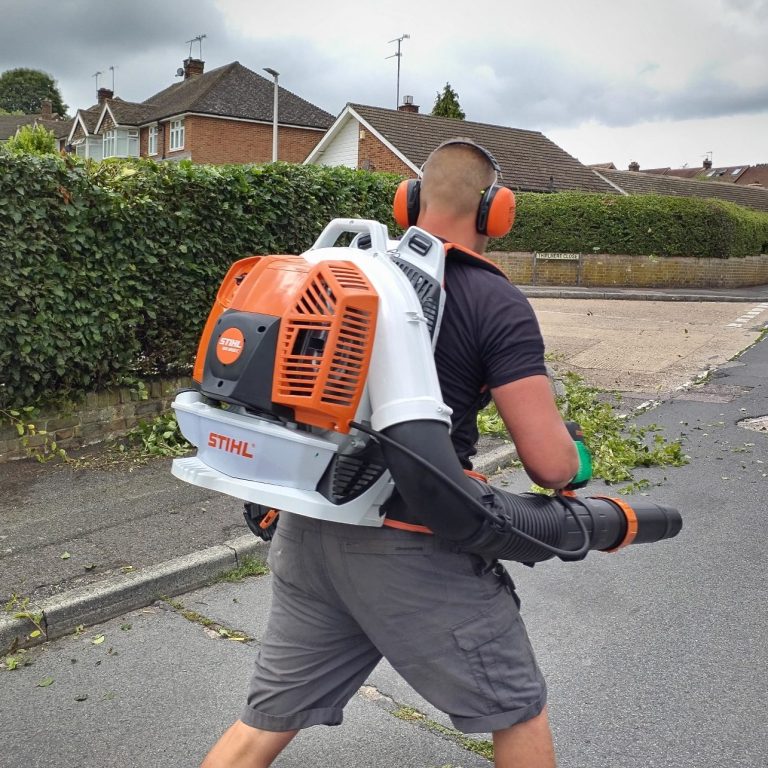 A man using a pole to clean a window from outside a two-storey house.