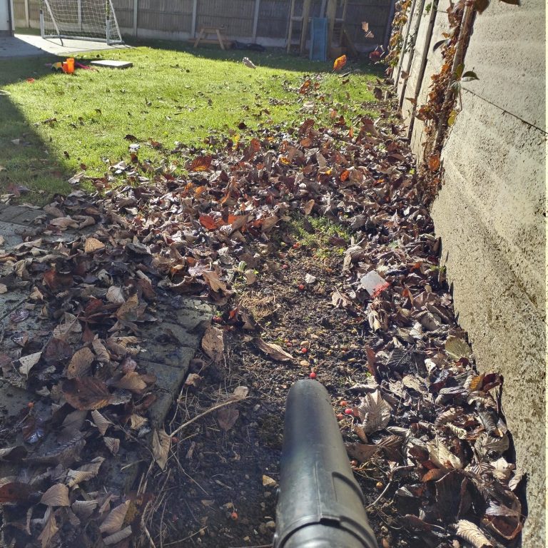 A person using a pressure washer to clean a patio surface.